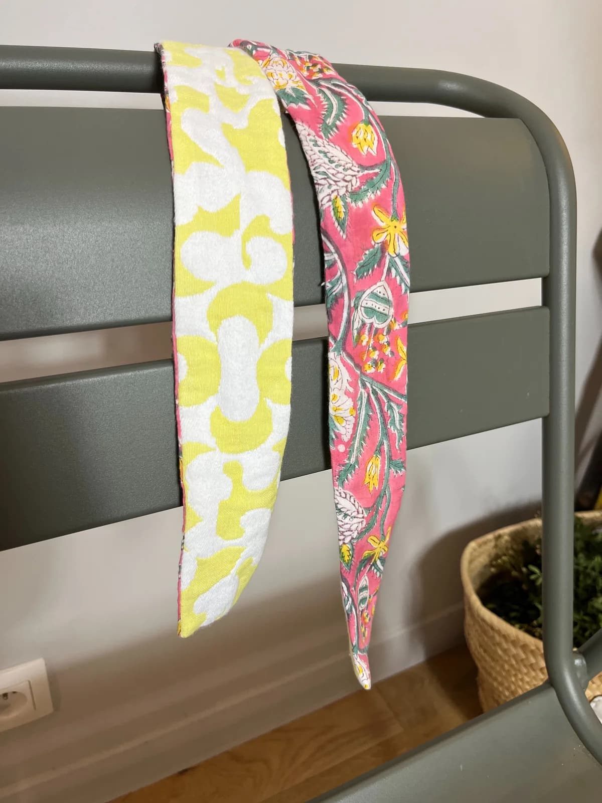Deux ceintures artisanales By Mésange sur dossier de chaise — tissu floral jaune et rose fleuri