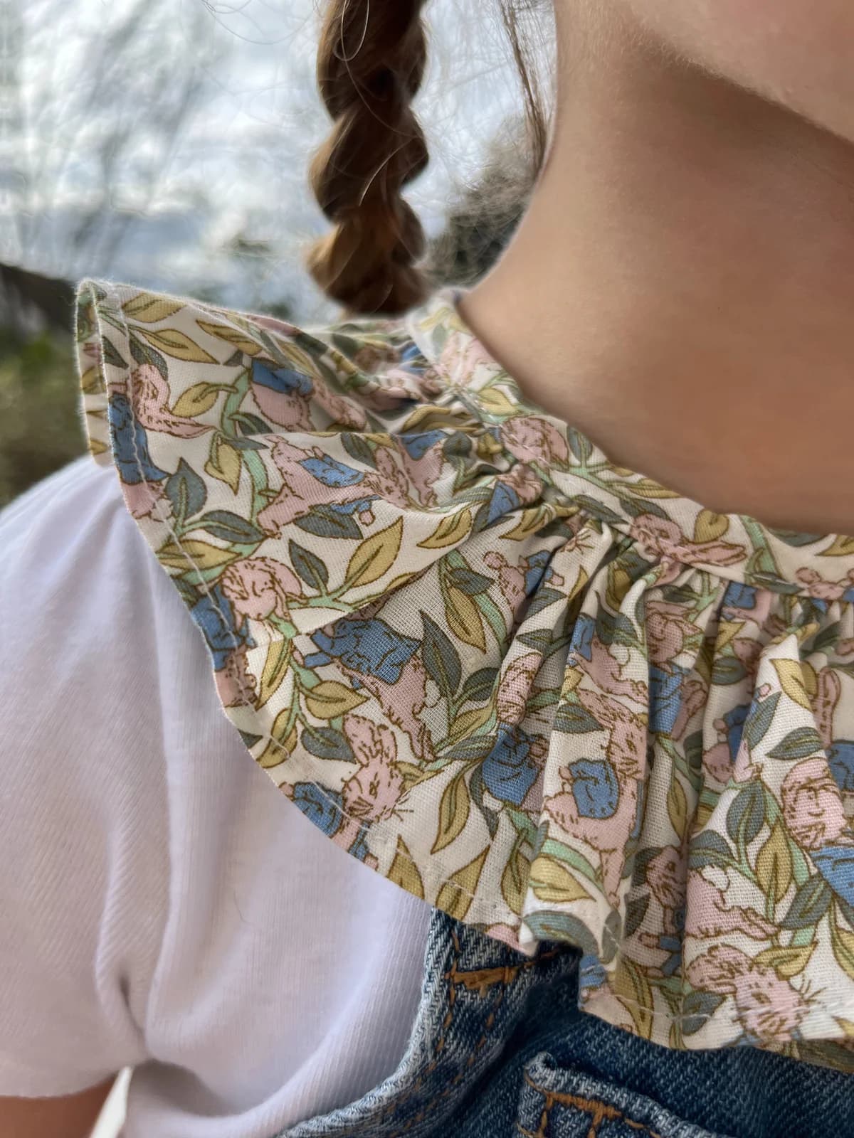 Gros plan d'un col claudine fleuri sur salopette jean enfant — détail couture By Mésange