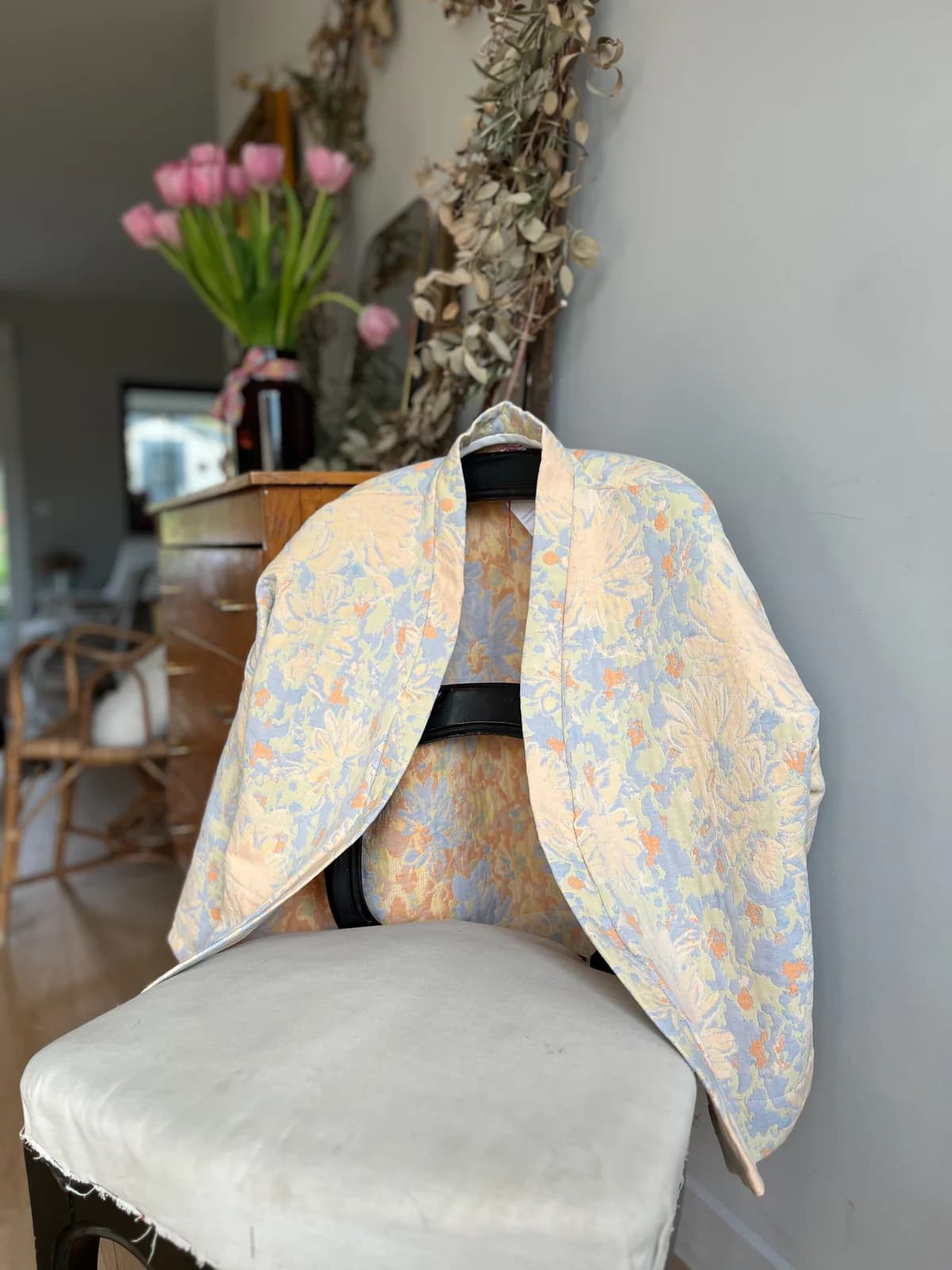 Veste jacquard fleurie pastel By Mésange posée sur une chaise — détail tissu