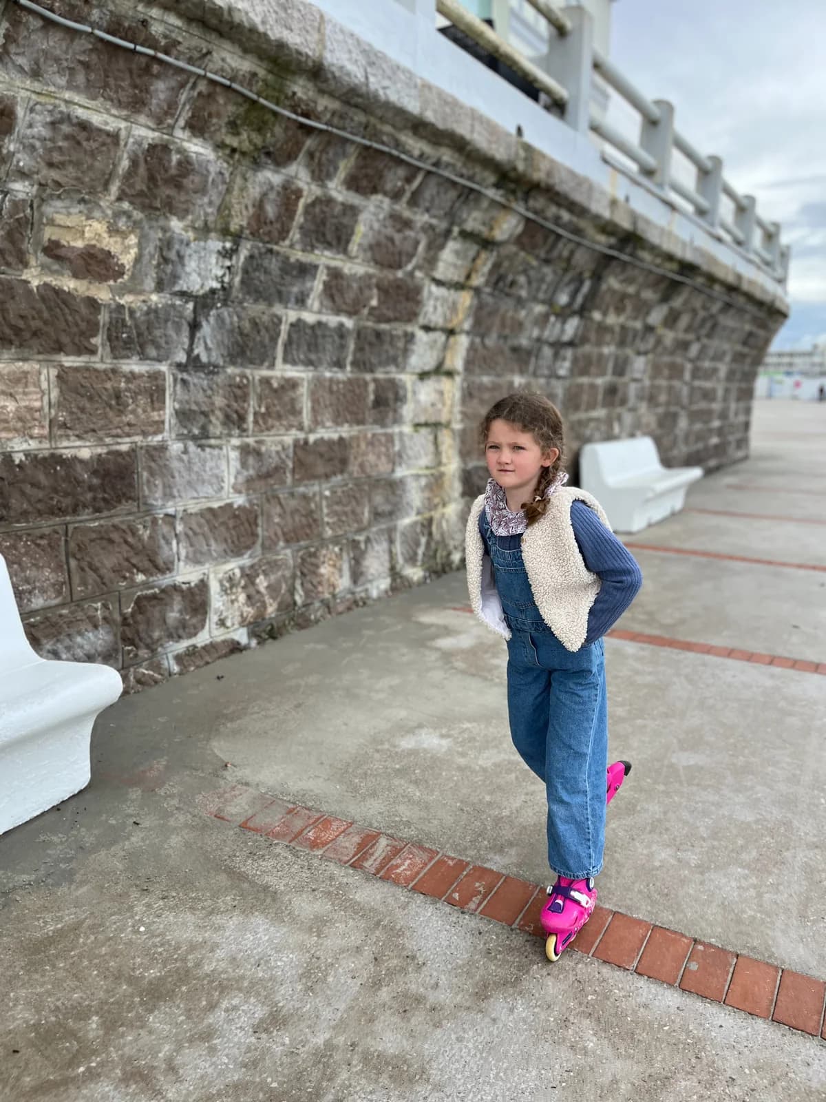 Fillette en patins à roulettes — salopette en jean et gilet berger blanc, bord de mer — By Mésange