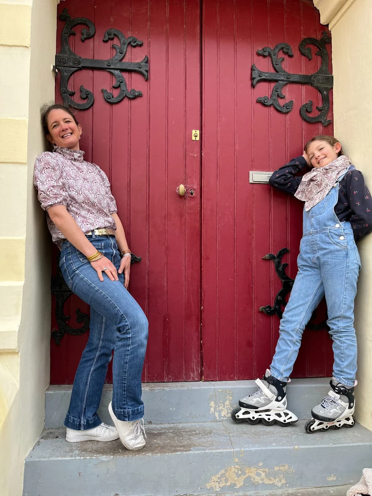 Mère et fille devant une porte rouge, blouse paon et salopette en jean avec patins — By Mésange