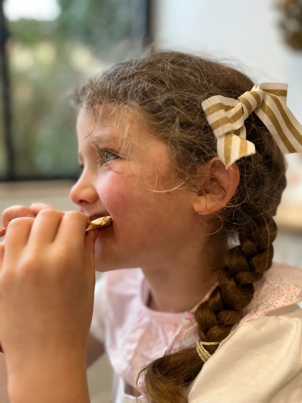 Portrait de fillette dégustant un biscuit, nœud rayé doré dans les cheveux — By Mésange