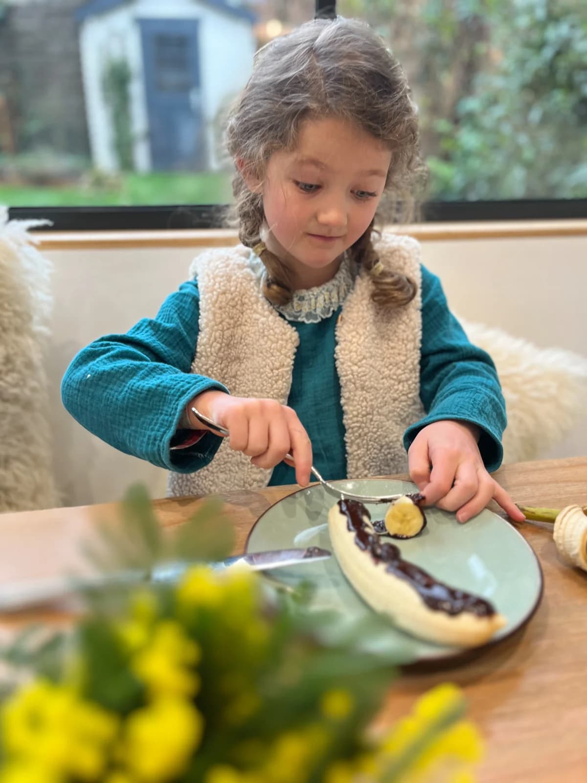 Fillette en robe gaze de coton bleu canard et gilet berger, au petit-déjeuner — By Mésange