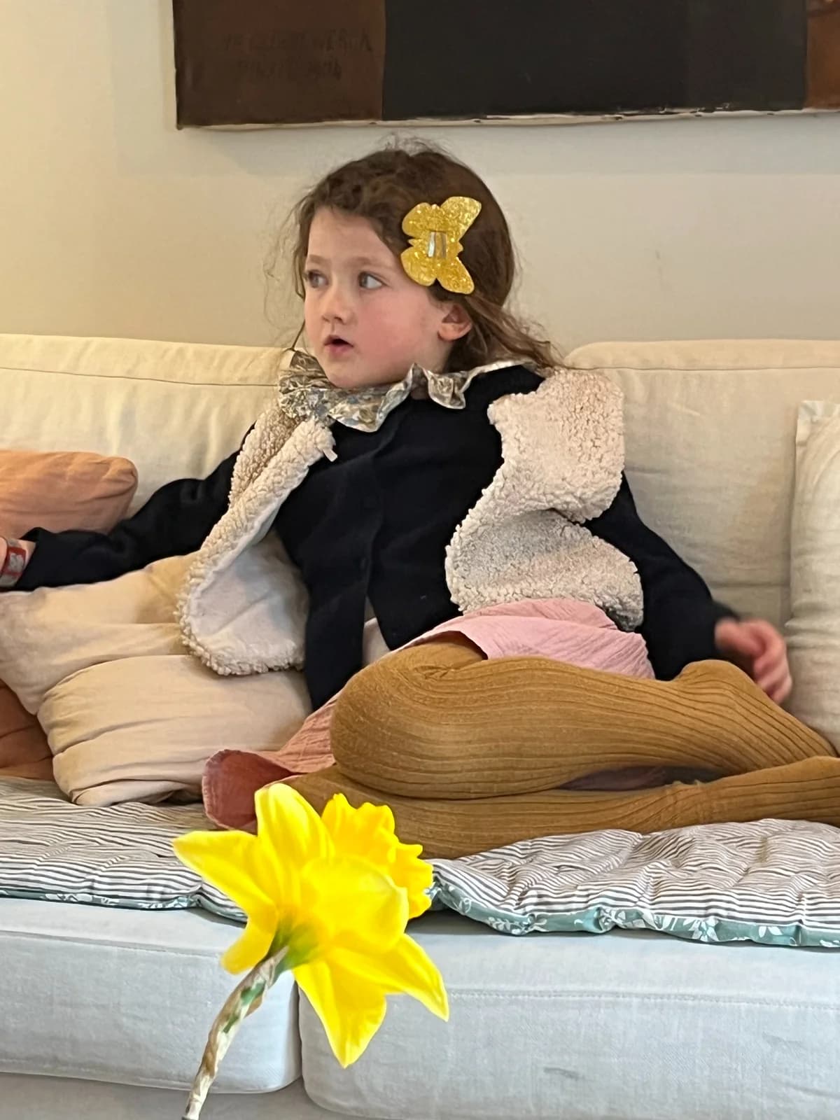 Petite fille sur le canapé en robe noire et gilet berger, barrette papillon dorée — By Mésange
