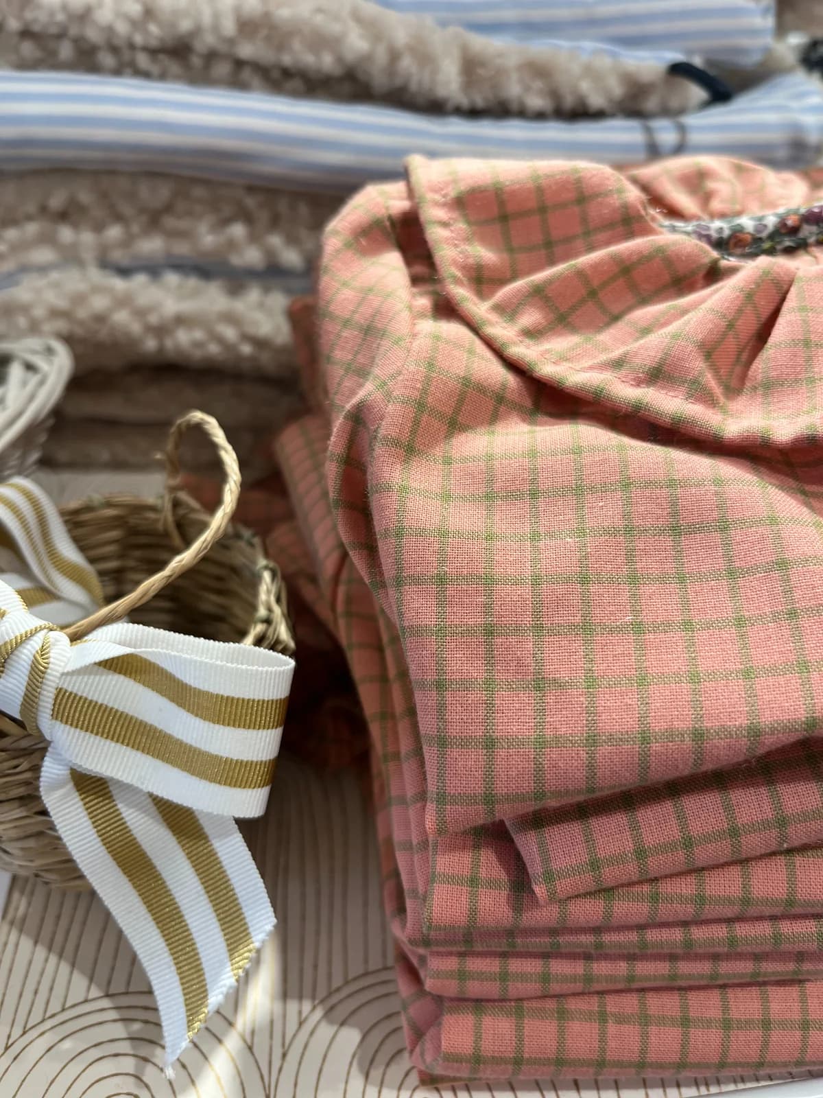 Tissu carreaux rose et vert soigneusement plié avec nœud rayé — détail couture By Mésange